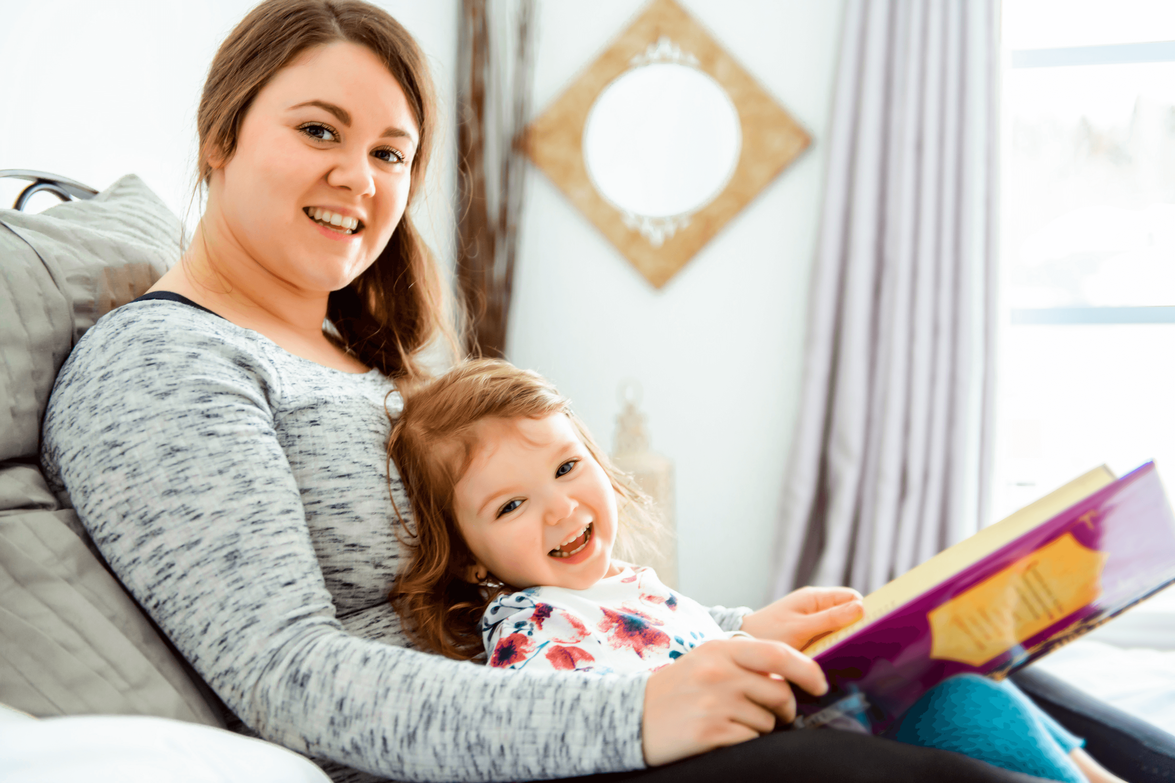 Mam and young girl reading together and smiling