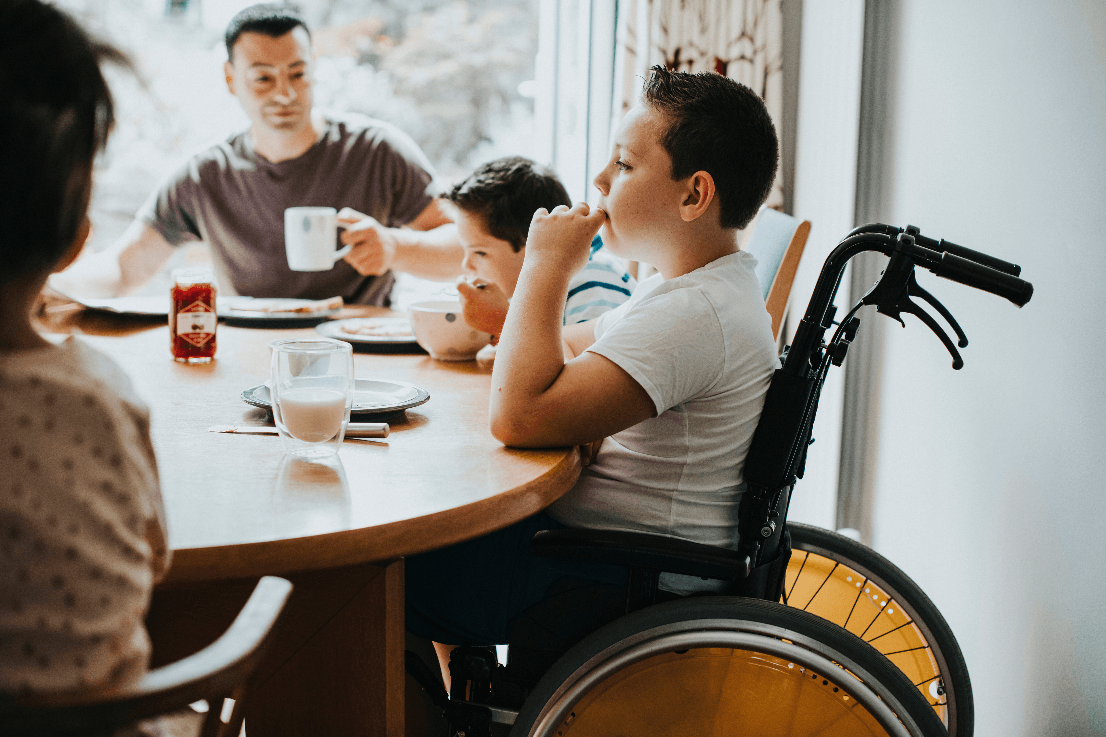 Young Person in a wheelchair sat at a table with his family