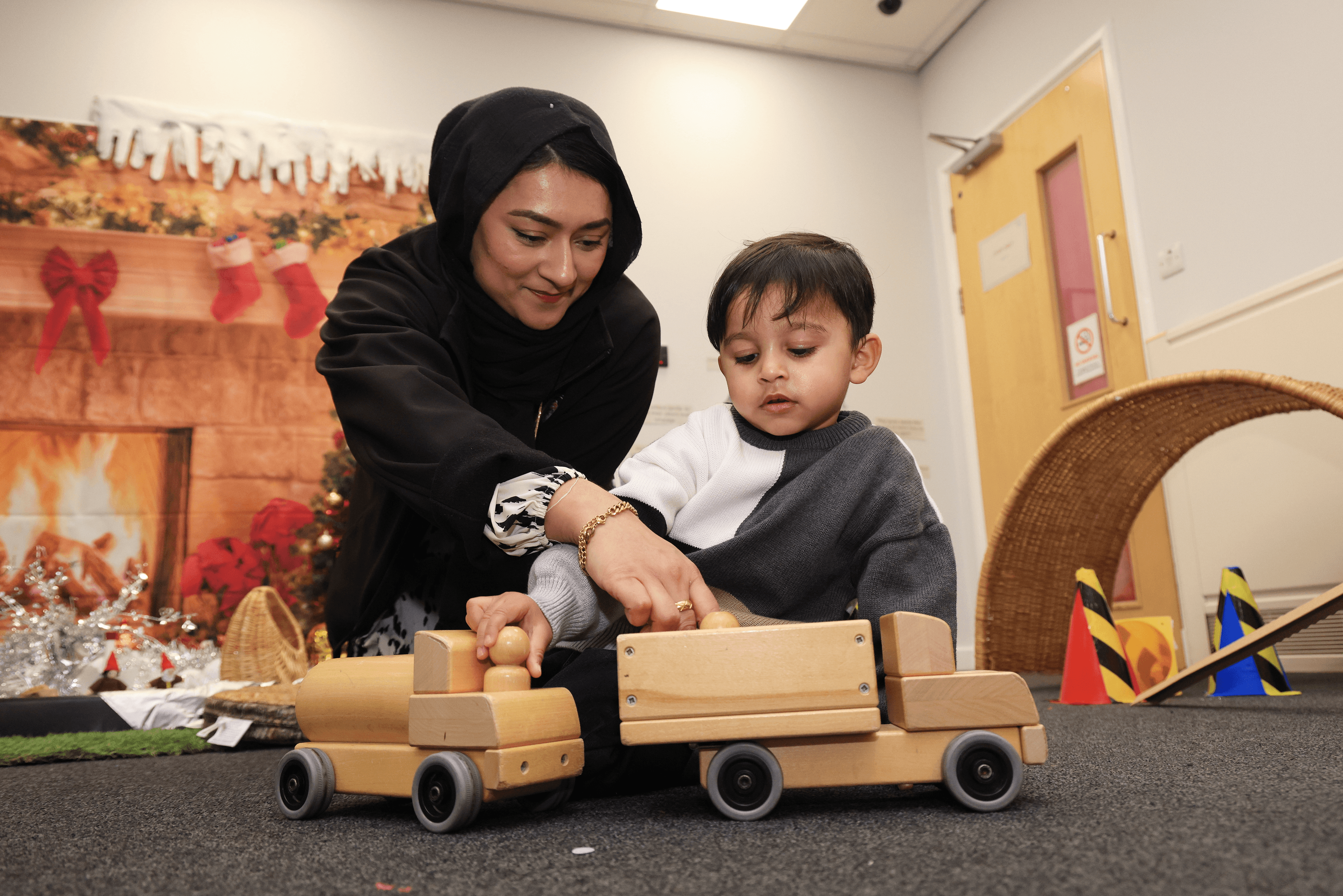 Mam and toddler playing with wooden toy train