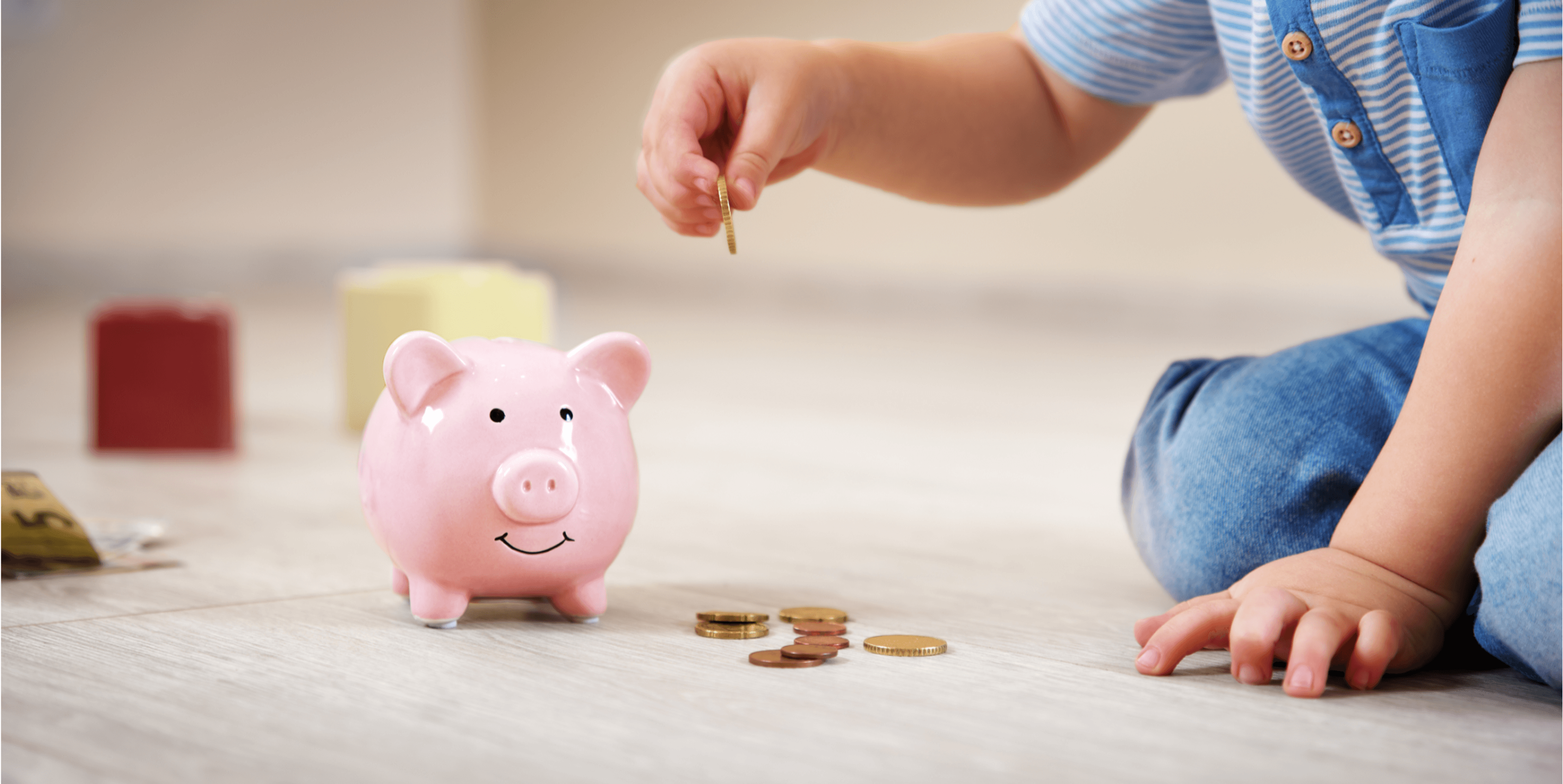 child putting money in a piggy bank